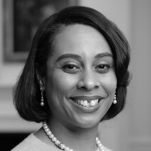 Portrait of smiling woman wearing pearl necklace and earrings with short hair.