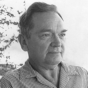 Black and white portrait of a man in a checkered shirt looking right with a neutral expression.