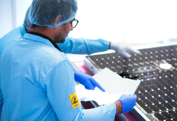 A large solar panel is being inspected by a Dhruva Space employee.