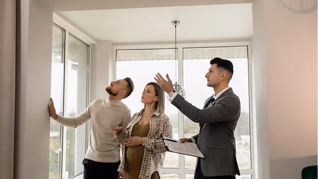 Real estate agent showing a couple a window in a bright modern apartment.