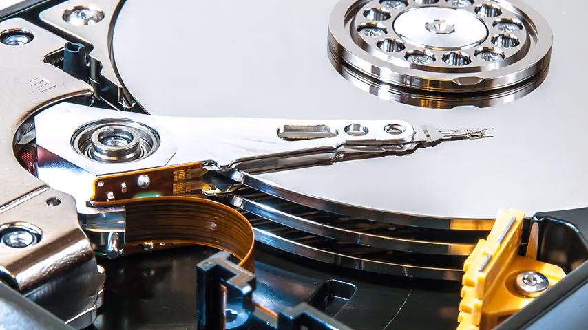 Close-up of an open hard disk drive showing shiny platters and read/write arm.