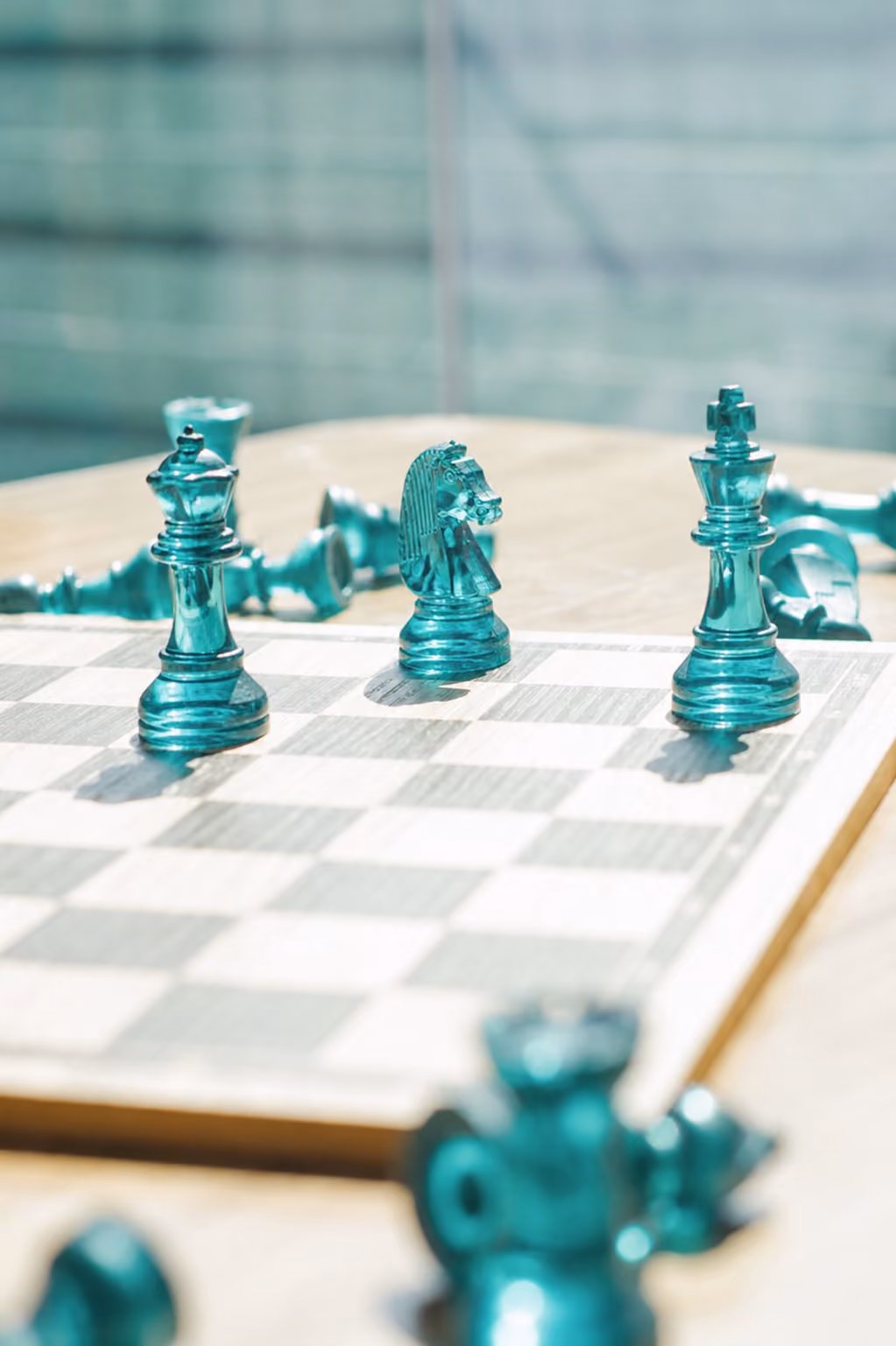 A chessboard with teal color glass chess pieces.