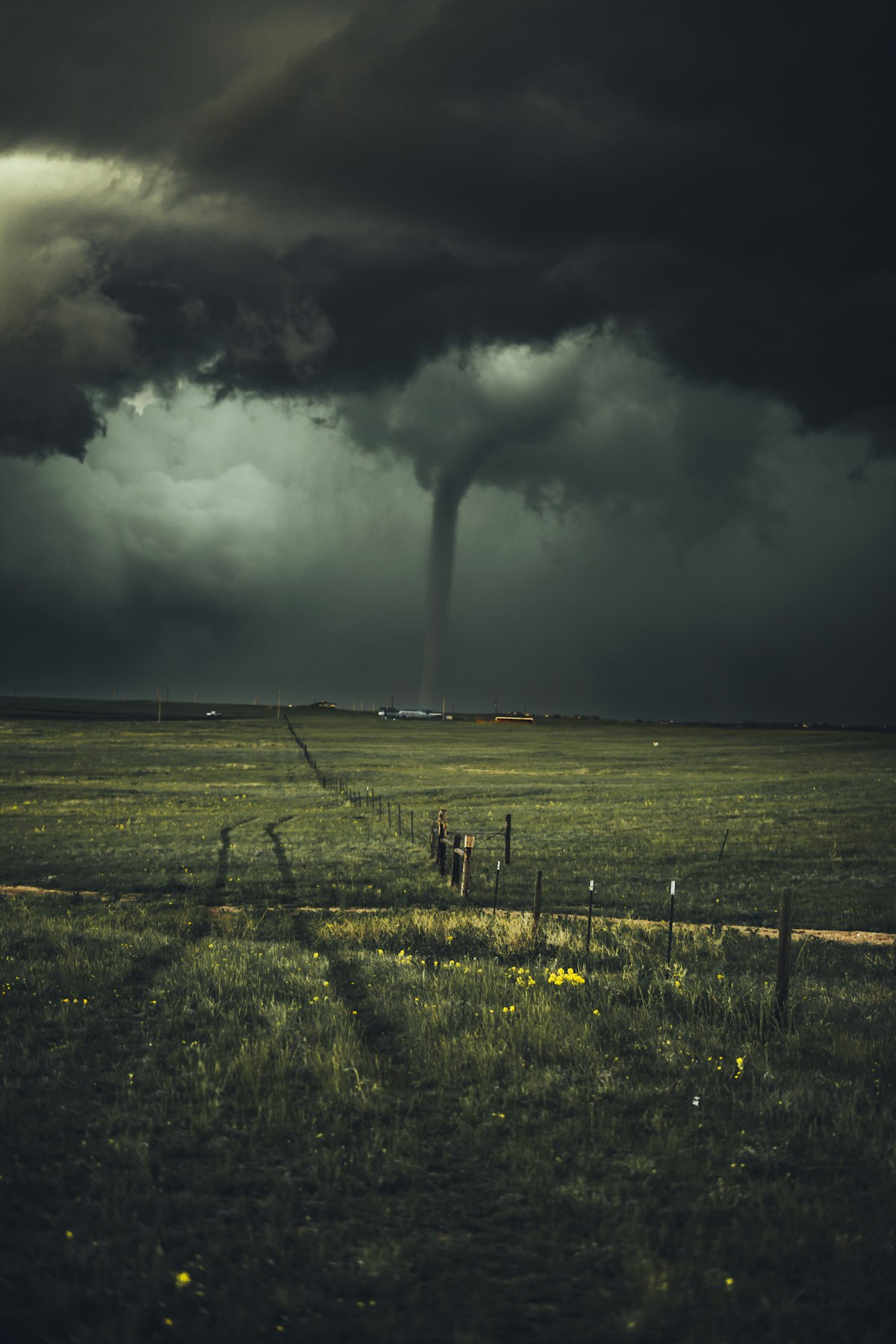 Tornado funnel cloud descending from dark storm clouds over open farmland in the Central United States