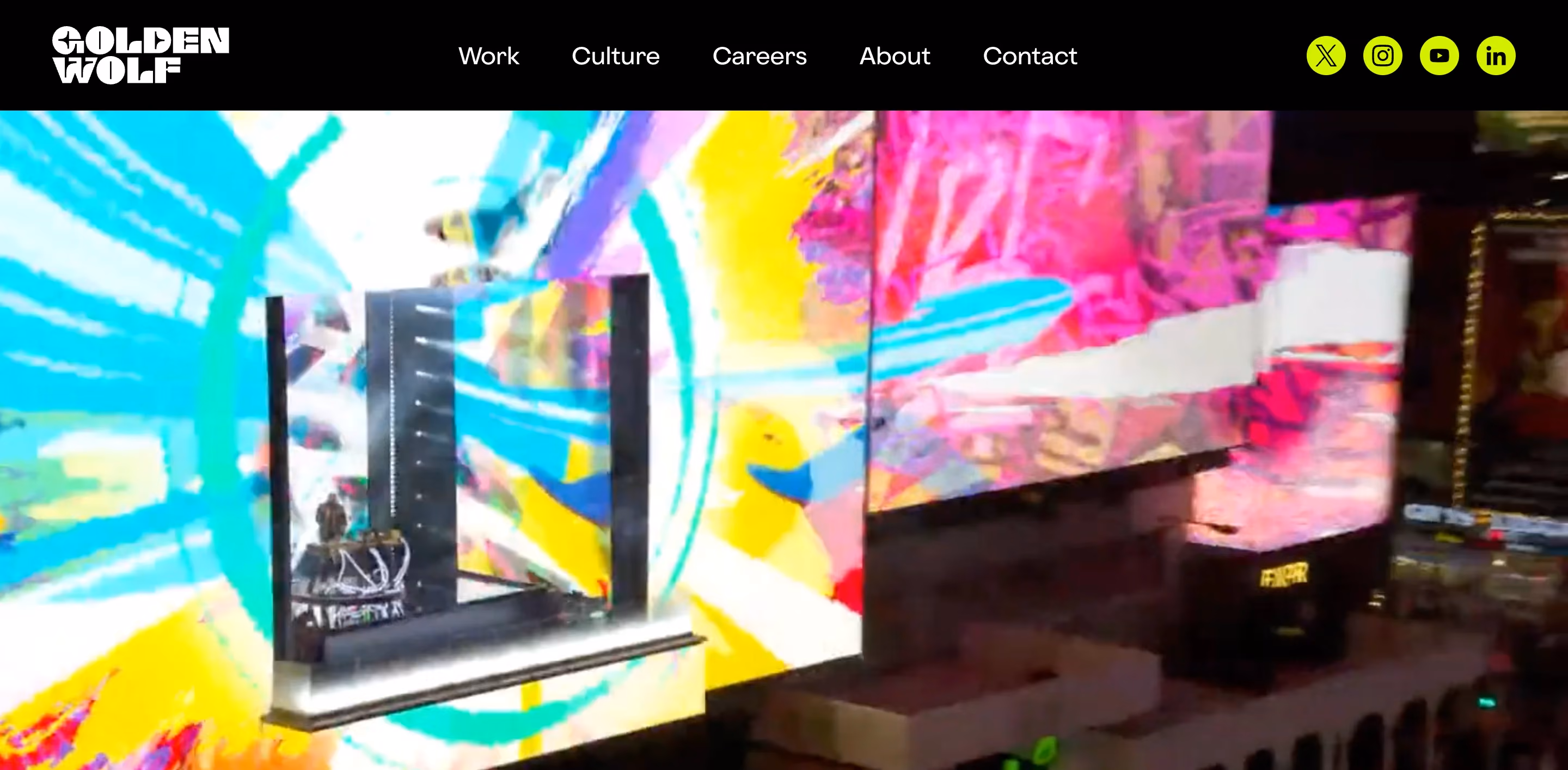 Golden Wolf motion design and animation studio homepage showing a vivid large-scale LED installation with bold multicolor abstract visuals and the Golden Wolf logo in white on a black background