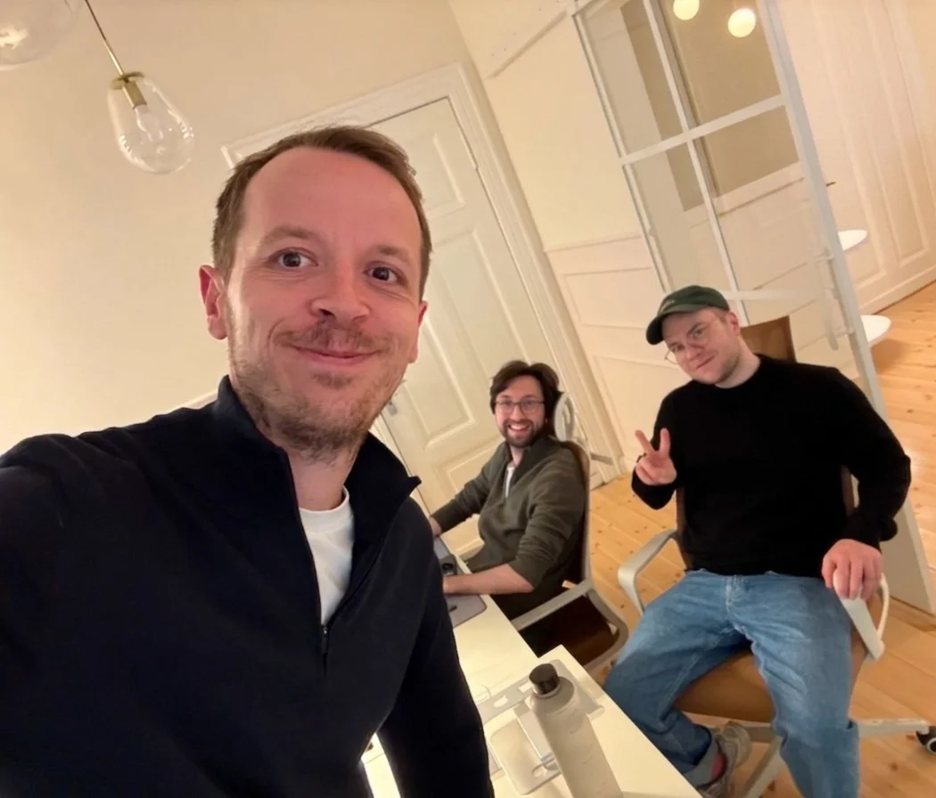 Gabriel Böker and two magier teammates in the office, with a screen in the background showing 844 total applications.