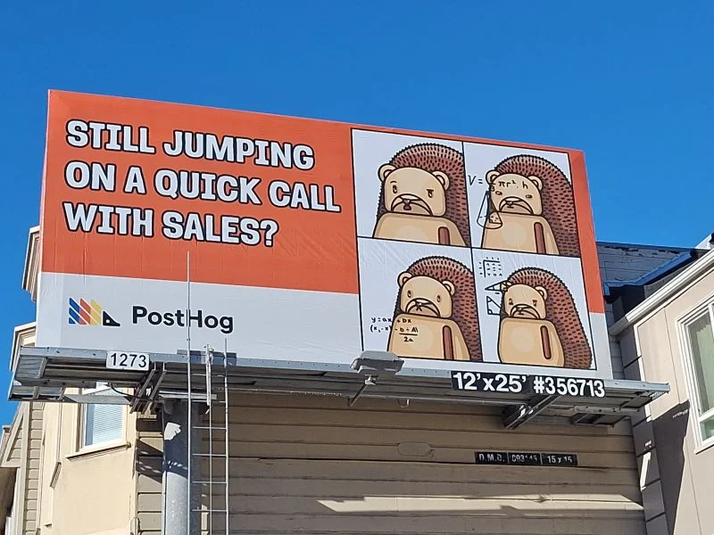 An orange and white outdoor billboard for PostHog reading 'Still jumping on a quick call with sales?' next to a four-panel comic of a hedgehog mascot working through a math equation on a whiteboard
