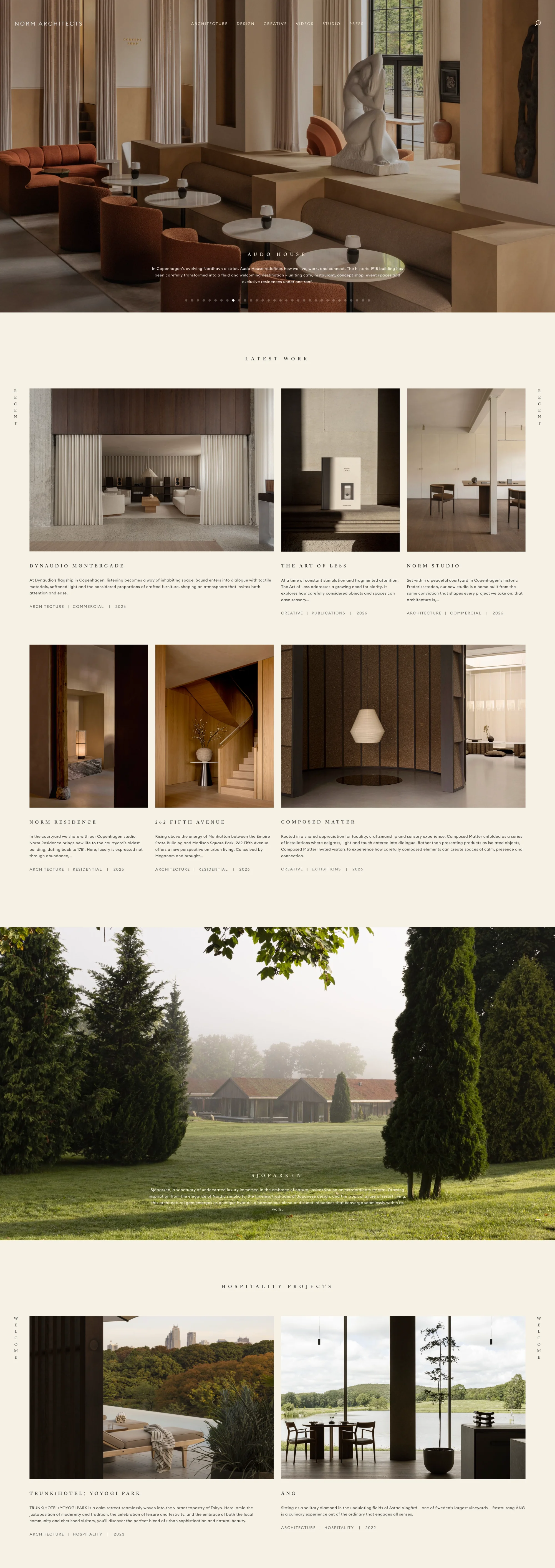 Norm Architects homepage hero showing the Audo House café interior with rust sofas, round tables, and a stone sculpture