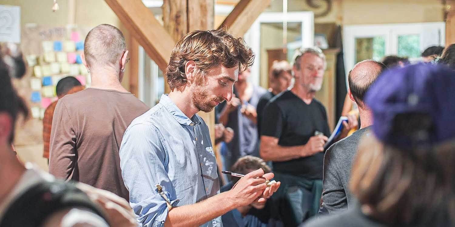 Un participant écrit sur un post-it pendant un événement organisé par l’association Hameaux Légers