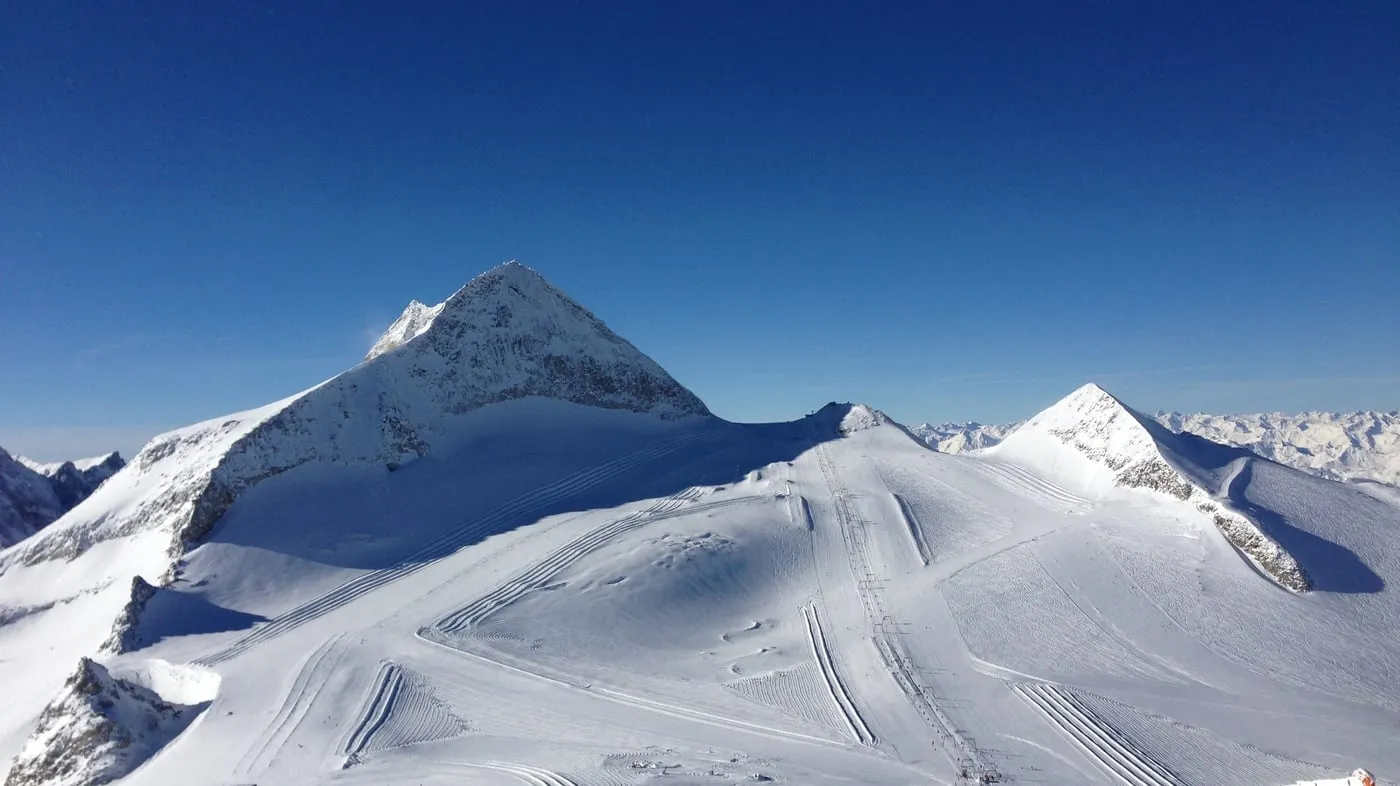 Gletschergipfel im Sonnenschein mit frisch präparierten Pistenspuren.