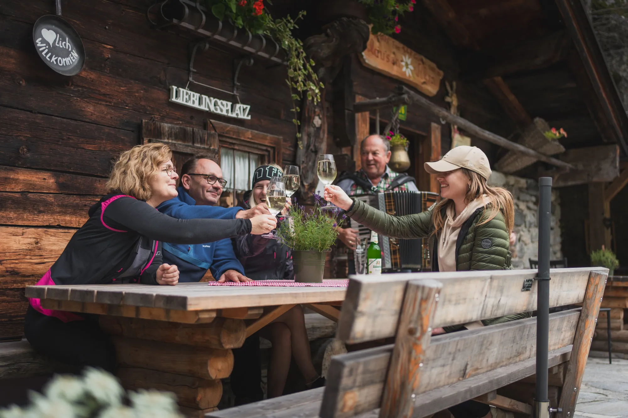 Wandergruppe stößt bei der Einkehr auf der Terrasse einer Almhütte an.