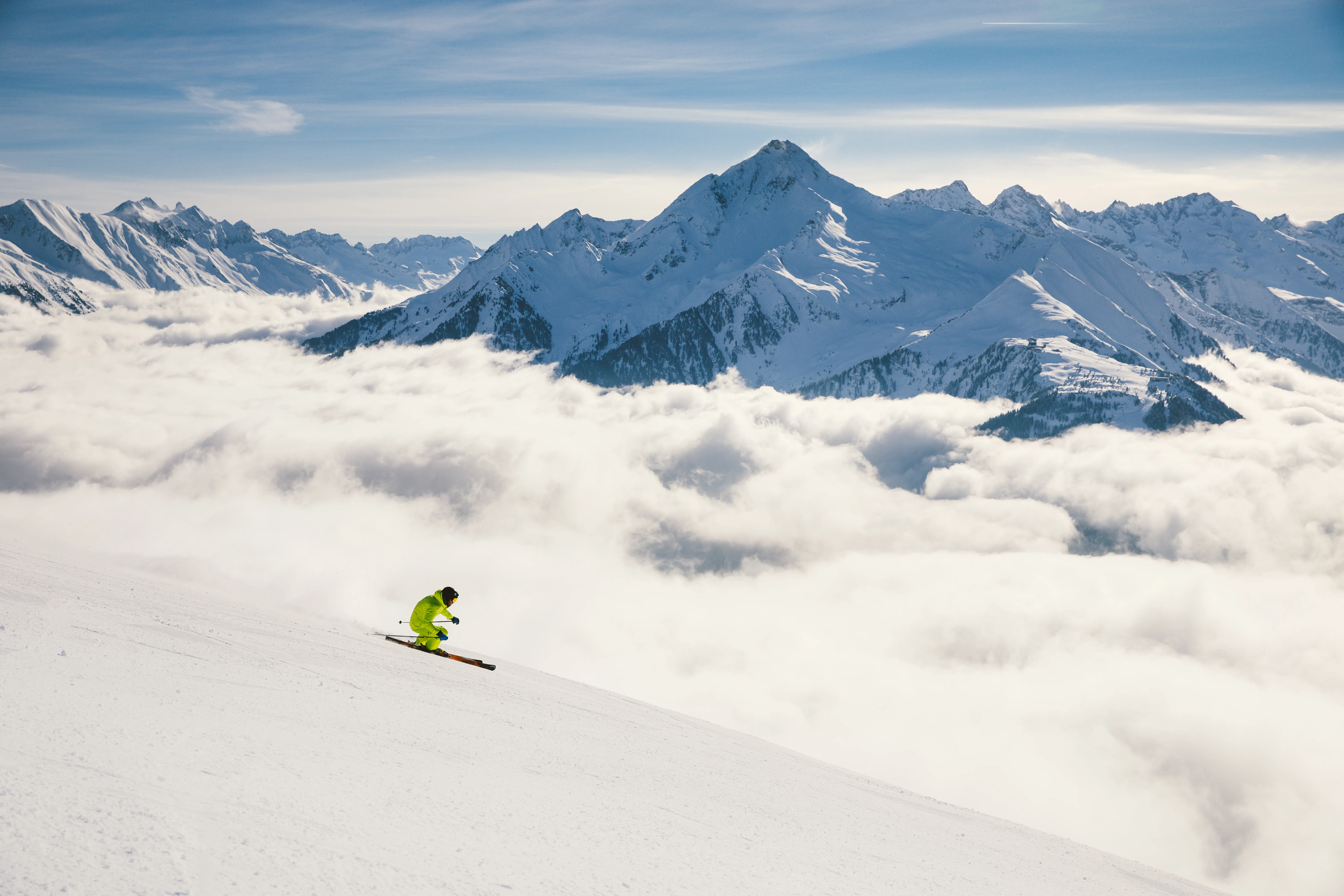 Skifahrer auf einer Piste hoch über dem Wolkenmeer im Zillertal.