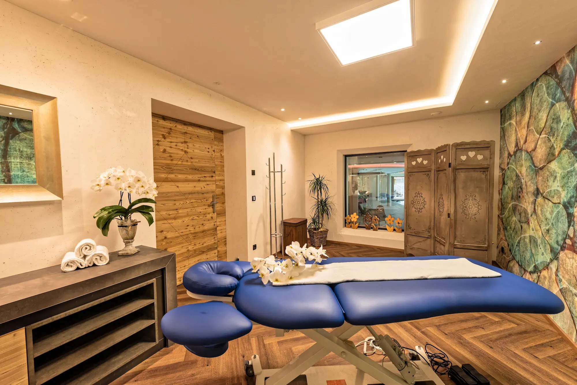 Massageraum mit Massageliege, Orchideen und Handtüchern im Alpin Spa.