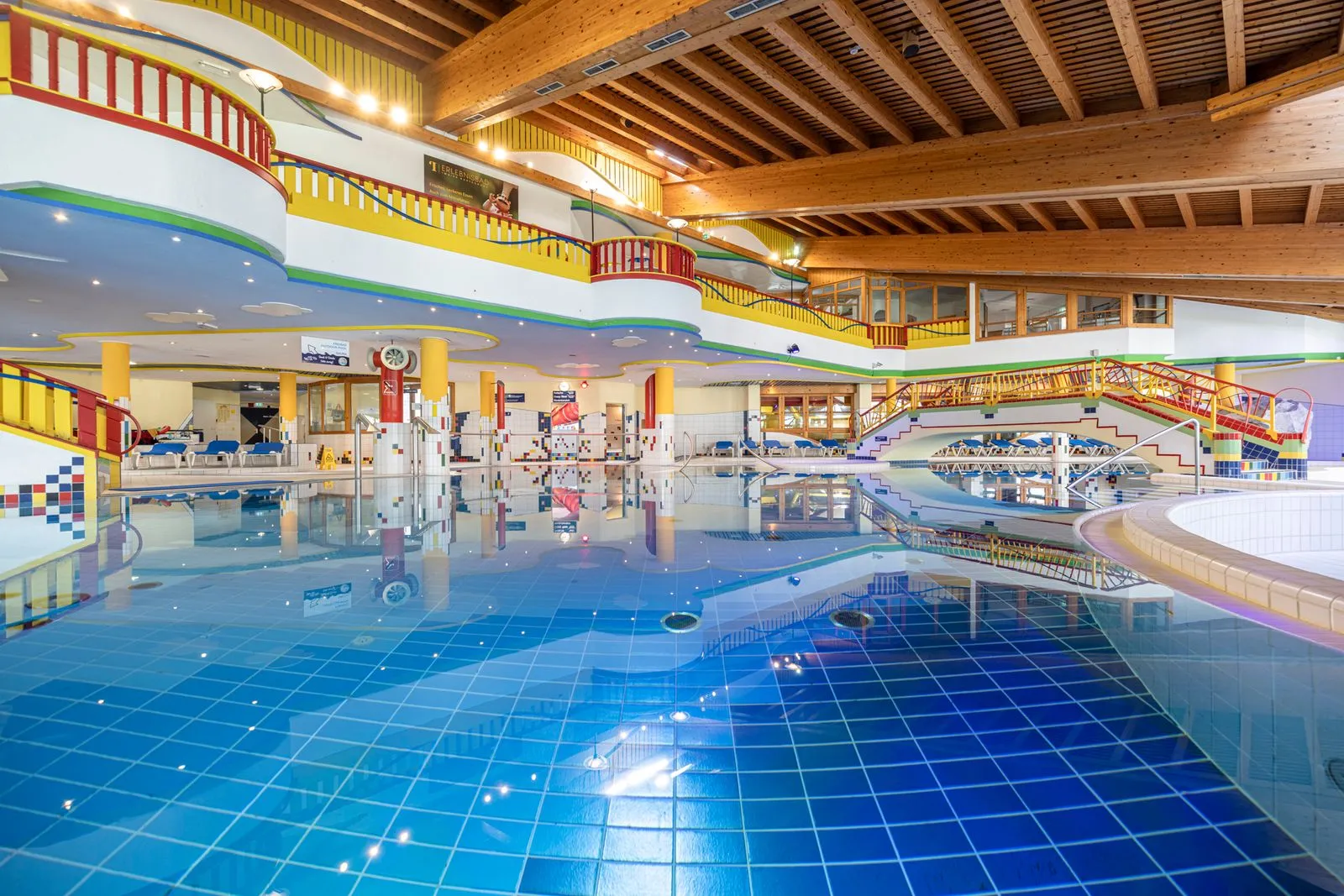 Hallenbad im Erlebnisbad Mayrhofen mit blauem Becken, Galerien und Holzdecke.