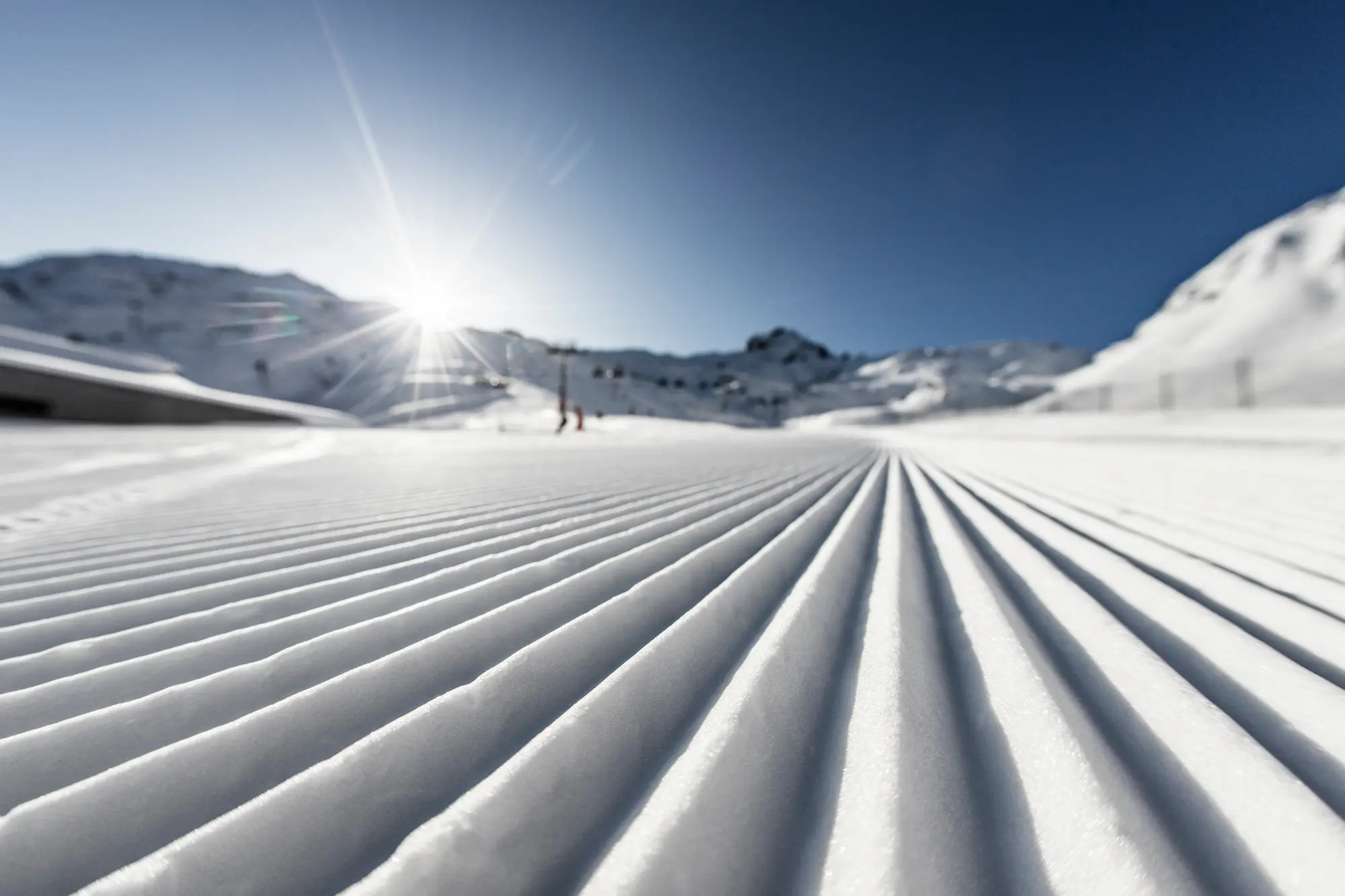 Skifahrer auf einer frisch präparierten Piste im Gegenlicht.