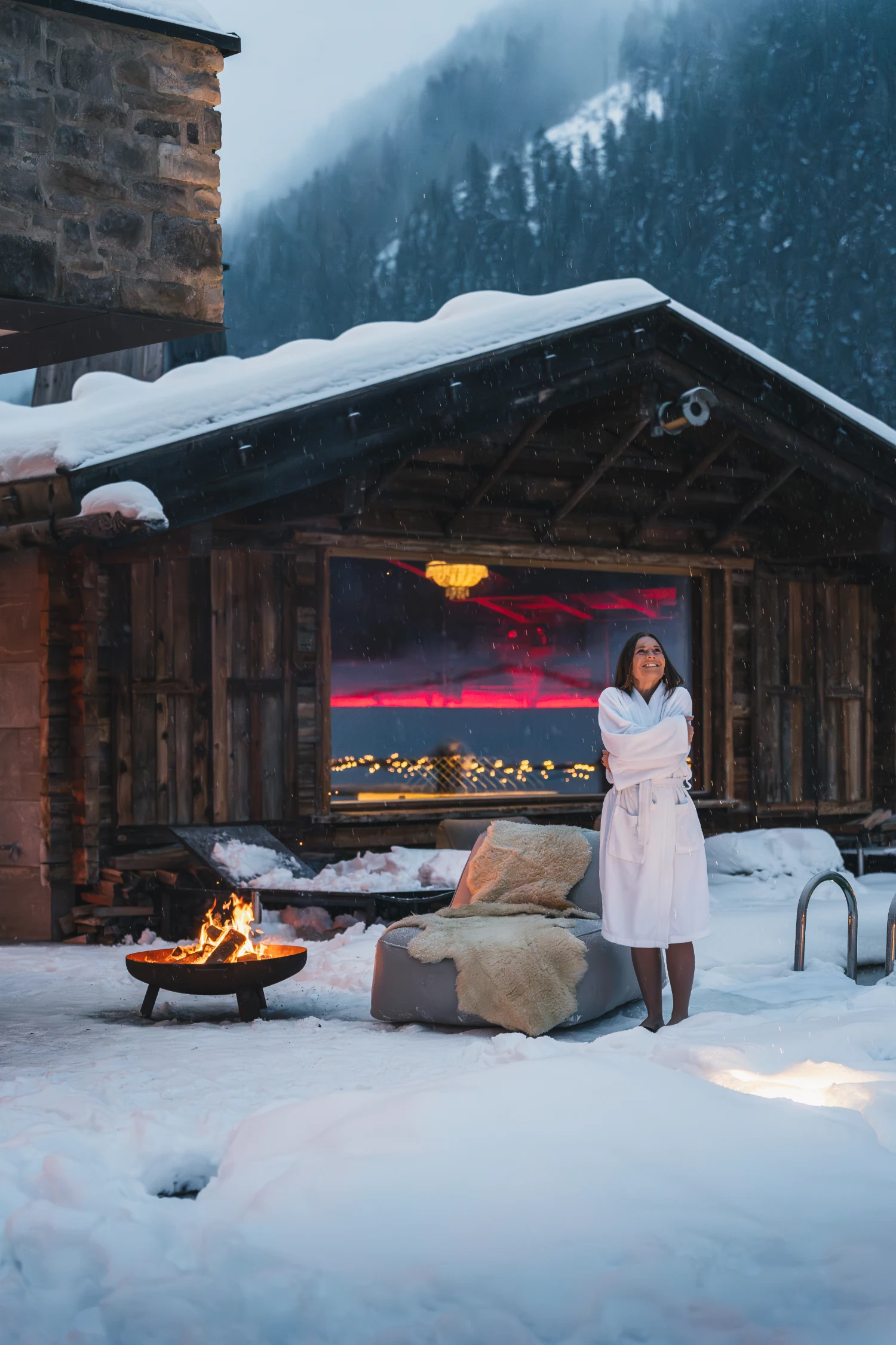Hotelgast im Bademantel vor der Außensauna im Schneefall.
