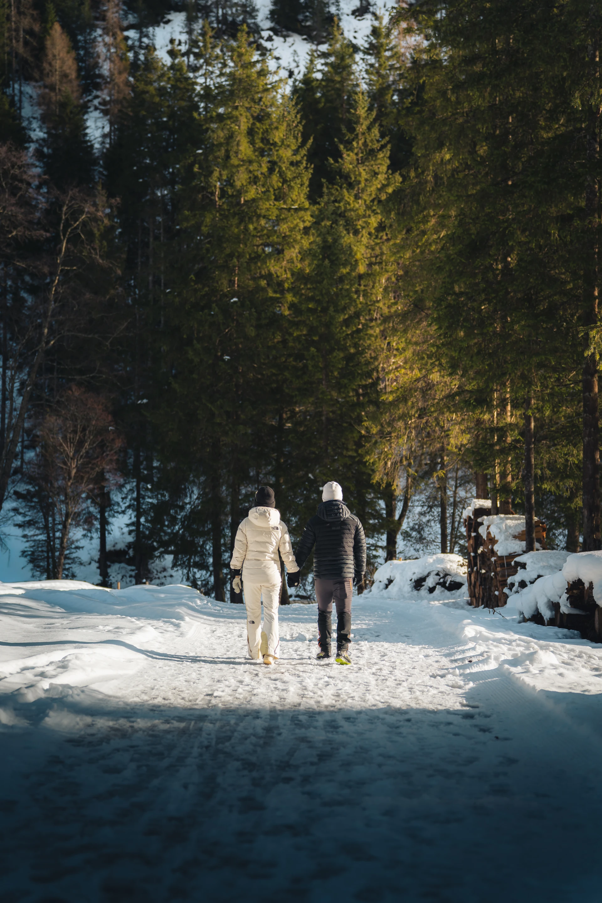 Paar beim Winterspaziergang auf einem verschneiten Weg am Waldrand in Tux.