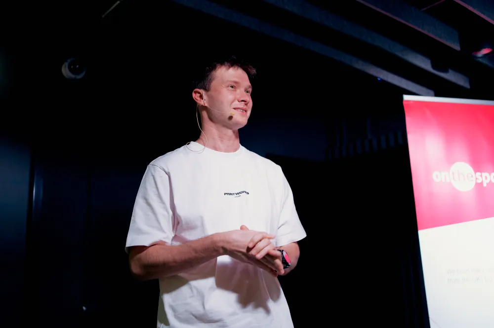 A speaker in a white T-shirt on stage at Inside game architecture