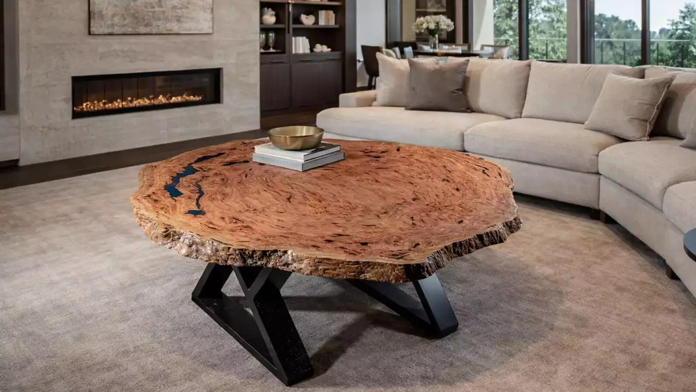 Bespoke wooden coffee table with natural edges and black metal legs in a modern living room with a beige sectional sofa and a fireplace.