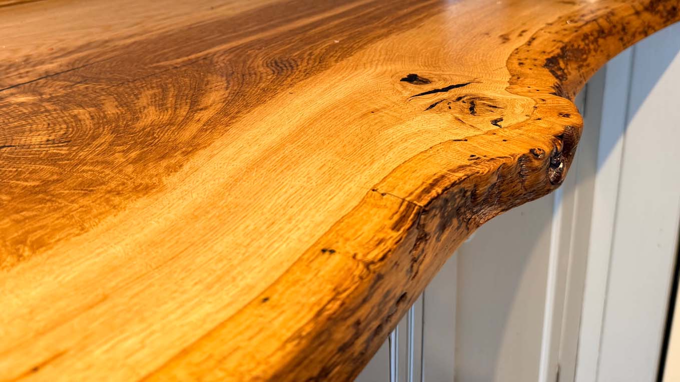 Close-up of a polished custom wooden kitchen countertop showing natural grain and live edge details.