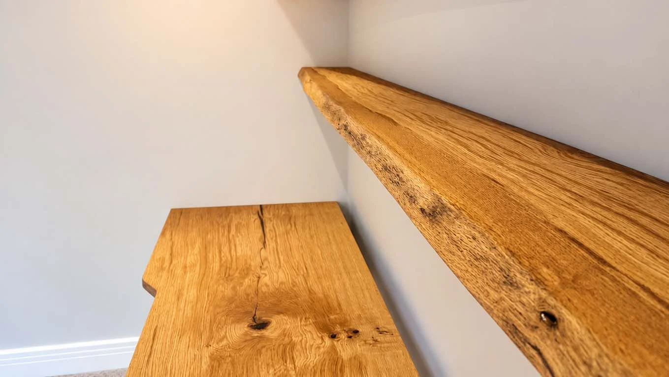 Natural-edge oak floating shelf above a fitted oak desk
