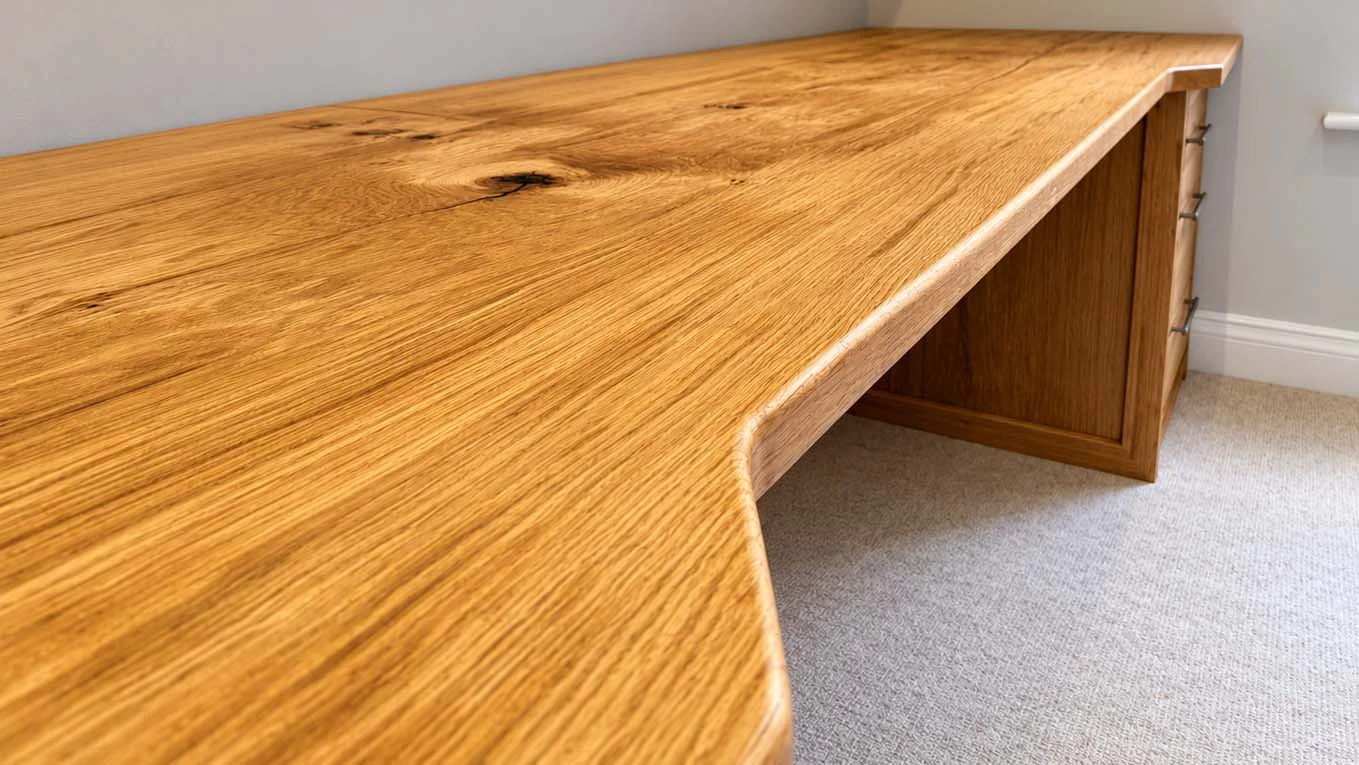 Close-up of a solid European oak desk top with a shaped front edge and natural knots