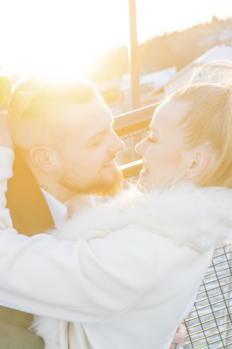 Couple embracing closely outdoors with golden sunlight shining behind them, creating a warm and intimate atmosphere.