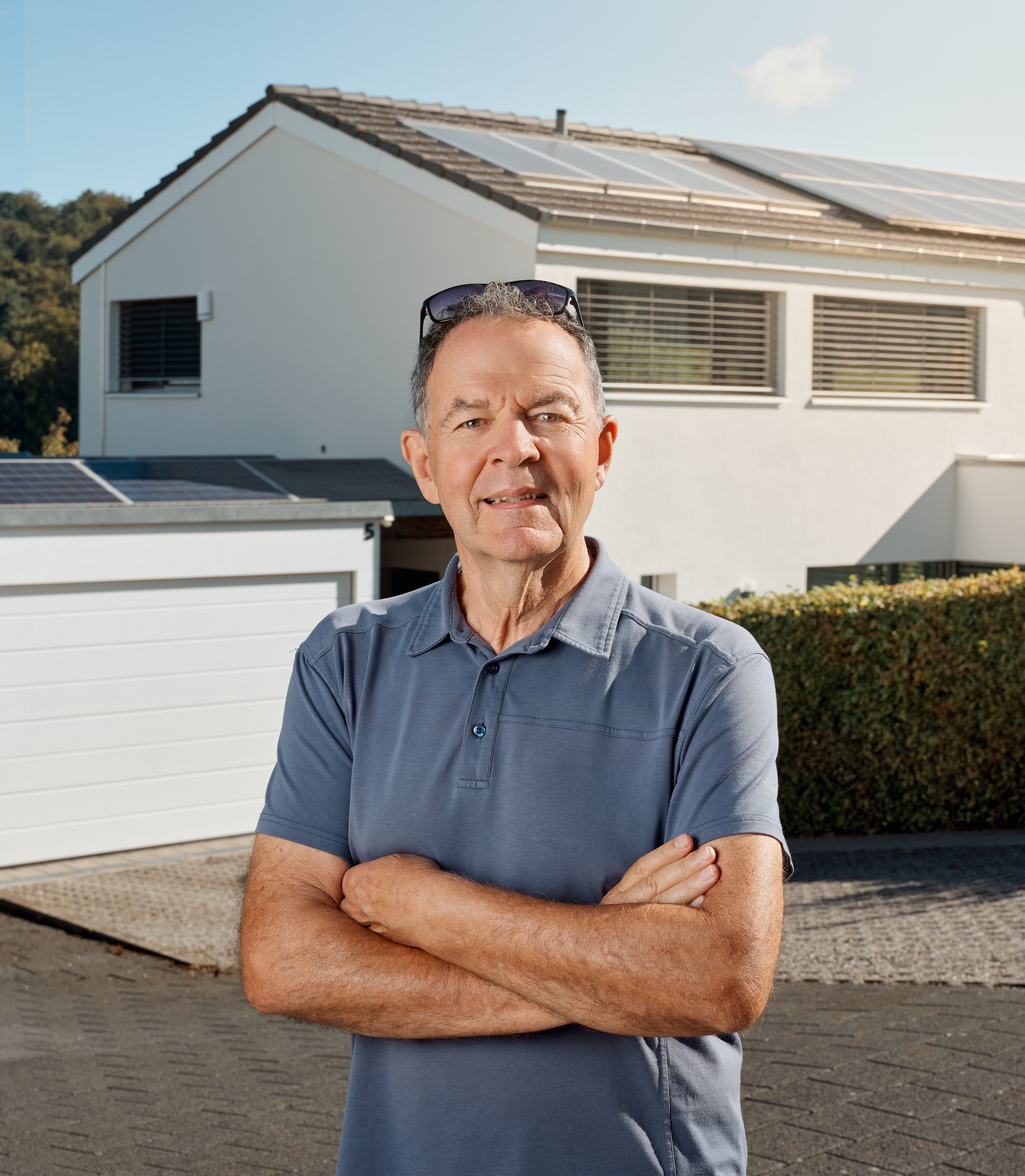 Jürg Gosteli, Initiant der Eigenverbrauchsgemeinschaft in Bäriswil, vor einem Wohnhaus mit Photovoltaikanlage.