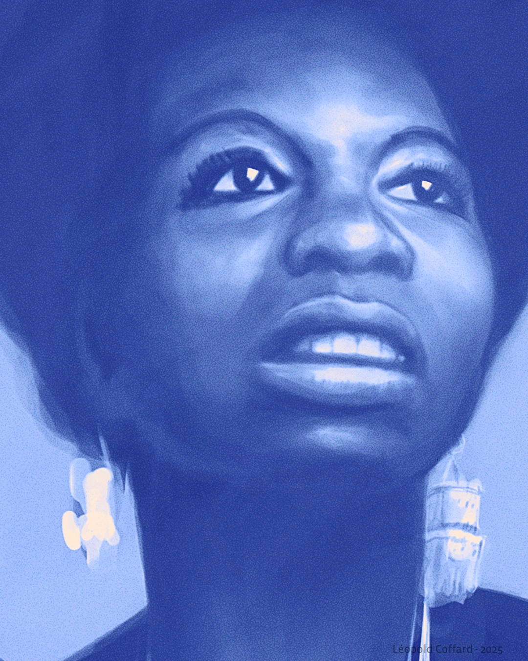 Close-up portrait of a woman with an afro hairstyle looking slightly upward, wearing dangling earrings.