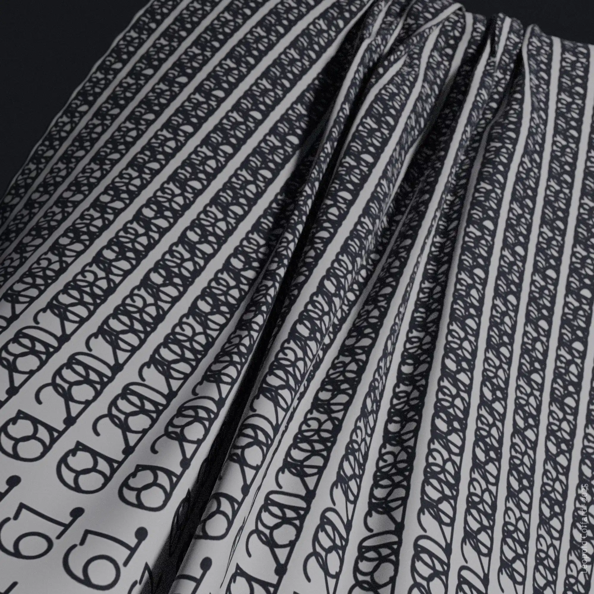 Close-up of folded fabric with repeating horizontal black numbers and circular patterns on a white background.