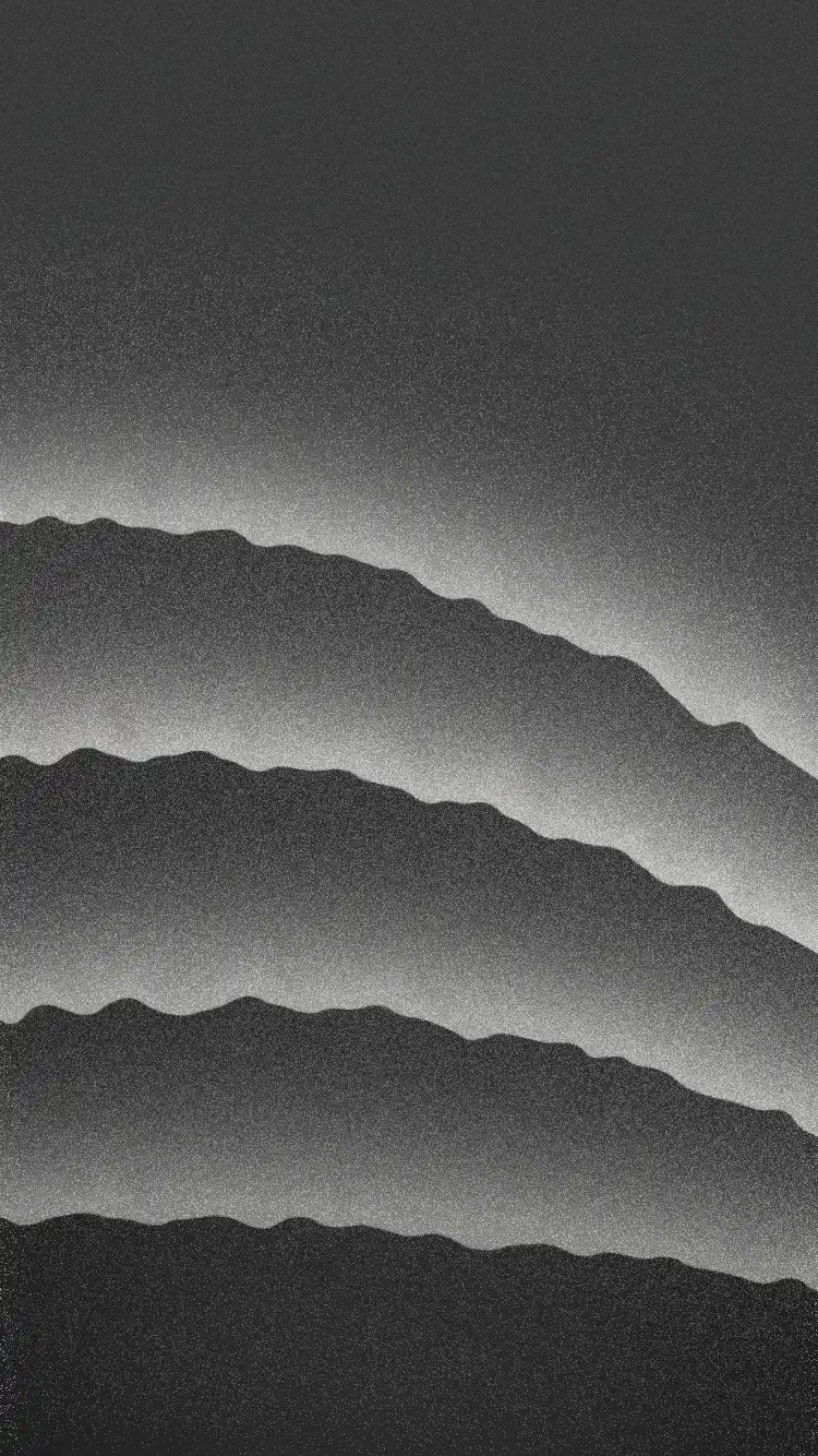 Monochrome layered silhouette of mountain ridges fading into the mist under a gradient sky.