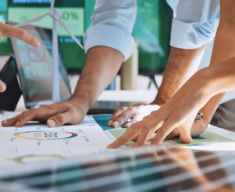 Ein Unternehmensplan mit sich darüber beugenden Mitarbeitenden