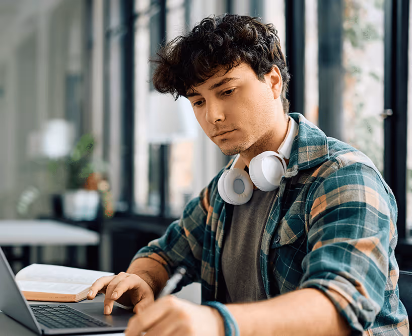 Ein Student beim Selbststudium mit Unterlagen und seinem Laptop