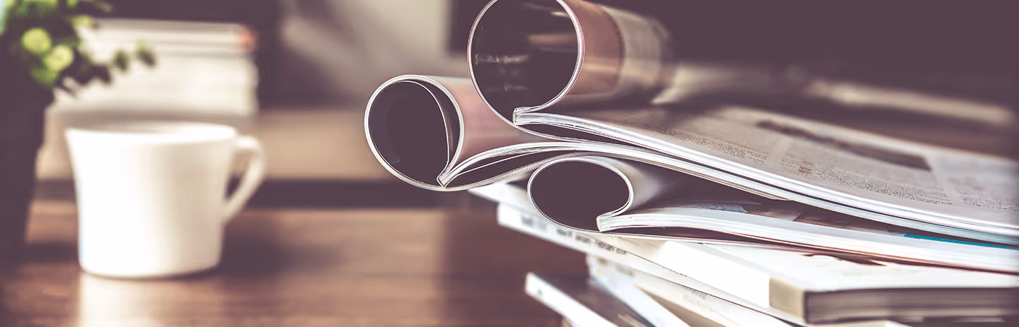 Ein Stapel mit Infomaterial und eine Tasse Kaffee auf dem Tisch