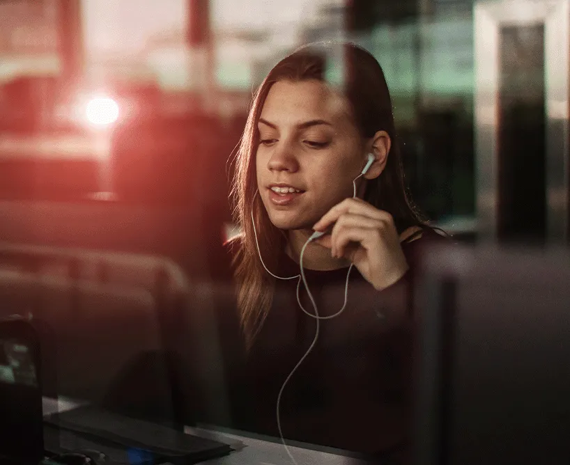 Junge Frau mit Kopfhörern arbeitet konzentriert am Computer – modernes Lernen im digitalen Zeitalter, passend zum Next Gen Bachelor Studium an der CBS.