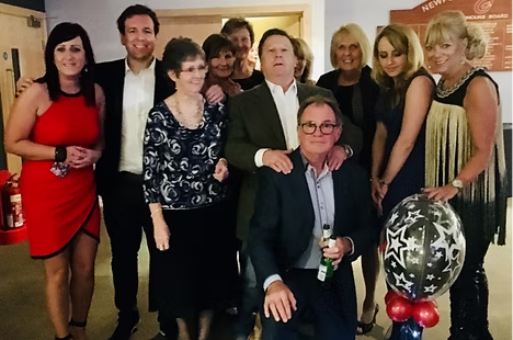 Diverse group of adults dressed up for a formal event, posing together