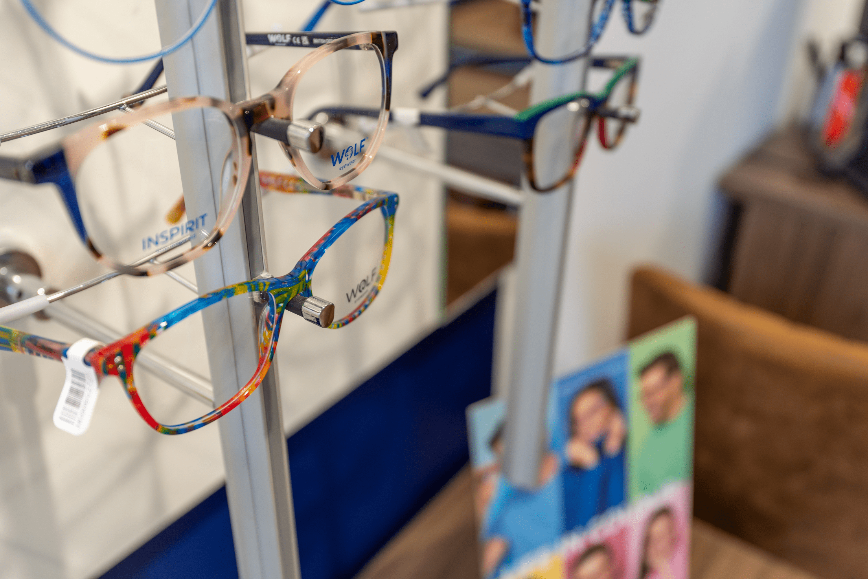 Colorful eyeglasses hanging on display rack in optical store