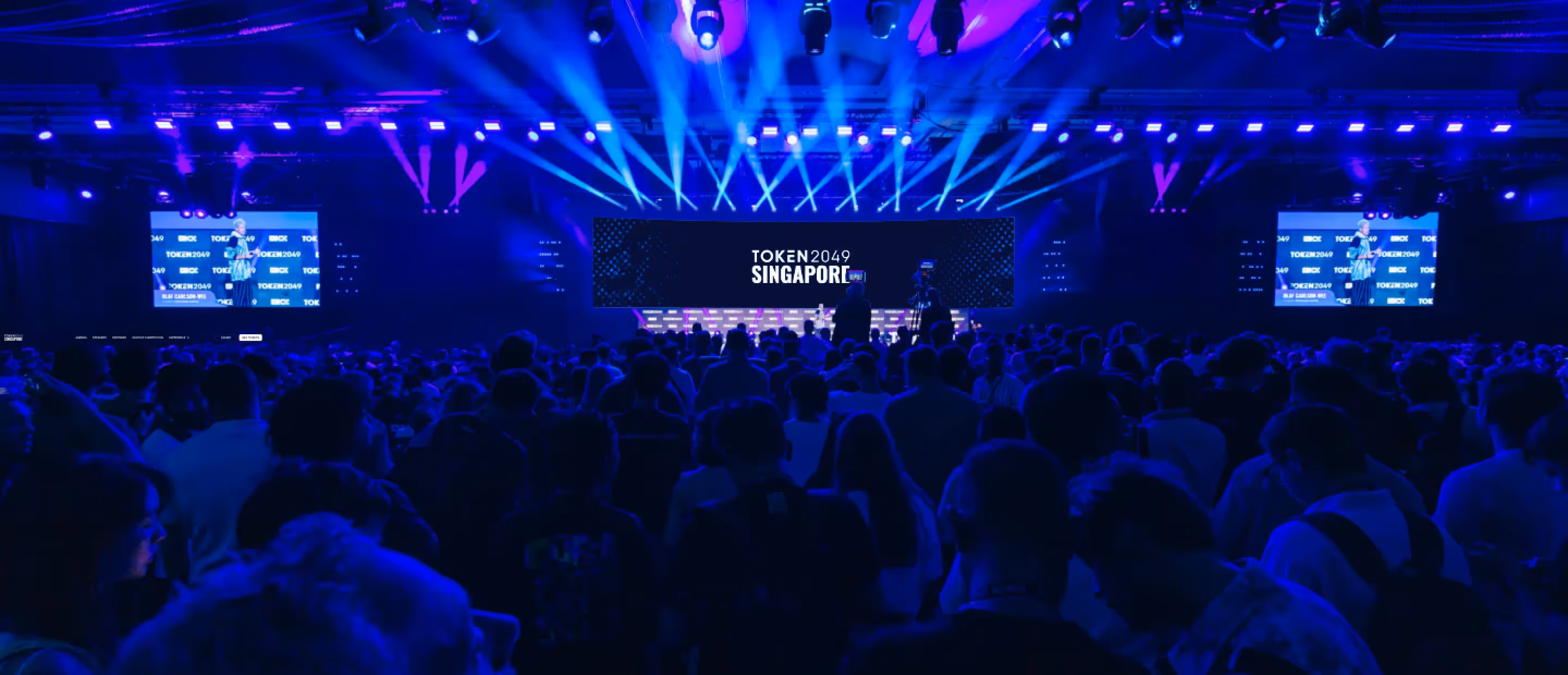 Token2049 conference in Singapore with packed audience and vibrant blue stage lighting