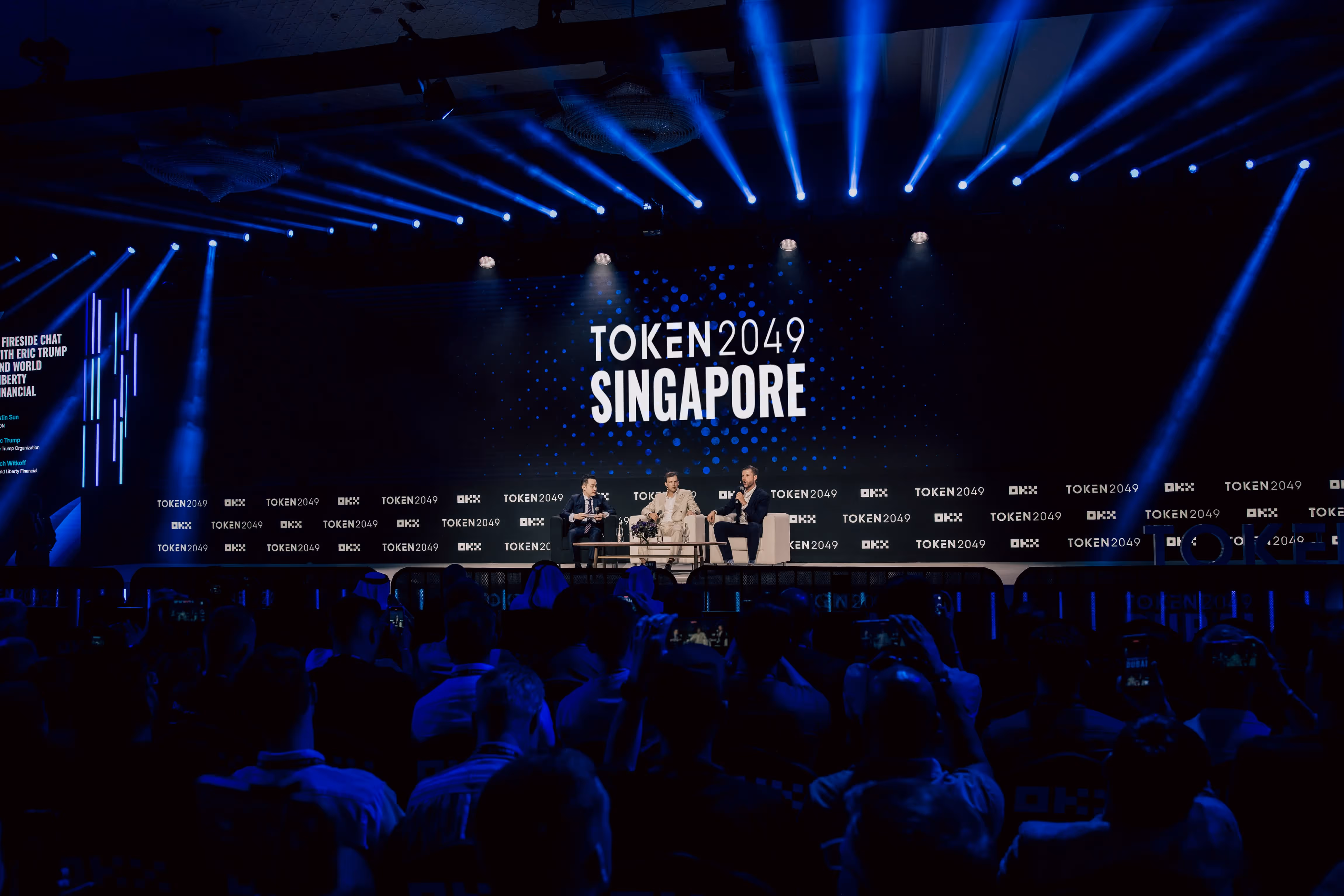 Token2049 conference panel on stage in Singapore with blue lighting