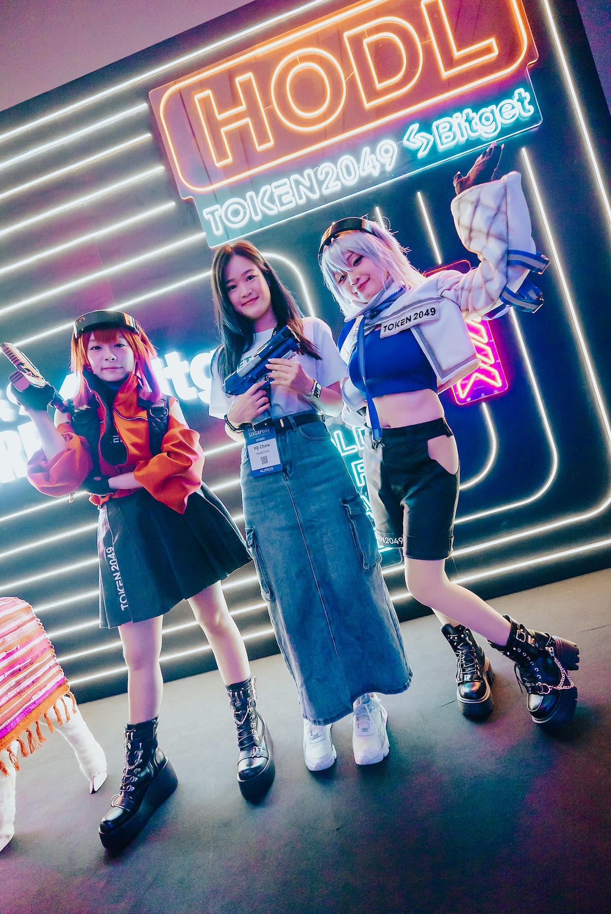 TOKEN2049 event in Singapore with cosplayers posing under neon HODL sign