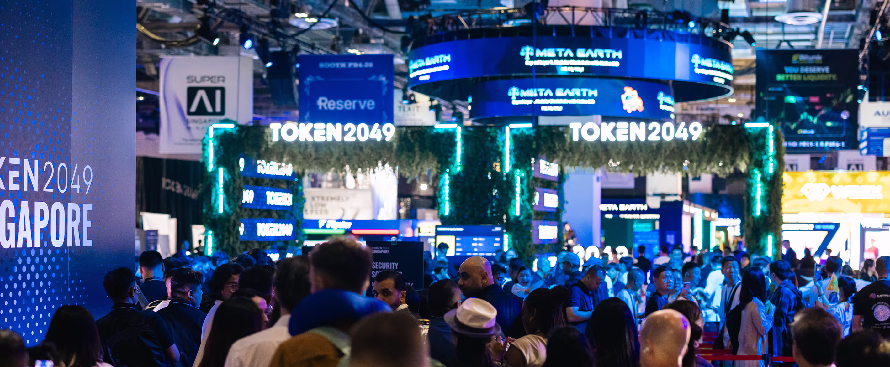 Crowded exhibition hall at TOKEN2049 Singapore with illuminated signage and booths in the background.