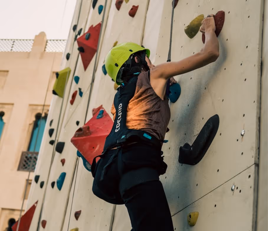 Attendee climbing a tall wall at TOKEN2049 Dubai