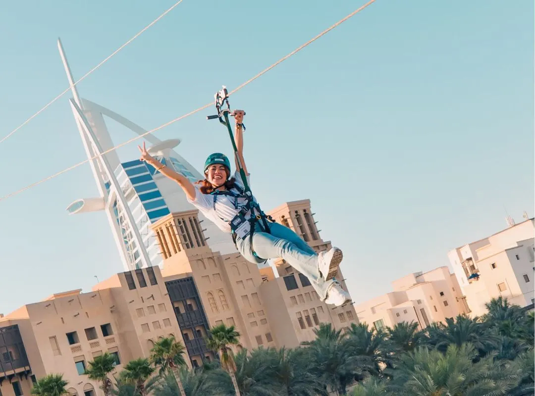 Attendee ziplining over TOKEN2049 Dubai venue with Burj Al Arab in the background