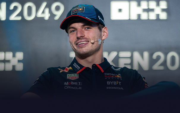 Max Verstappen wearing a Red Bull Racing team cap and shirt during a press event with a microphone headset.