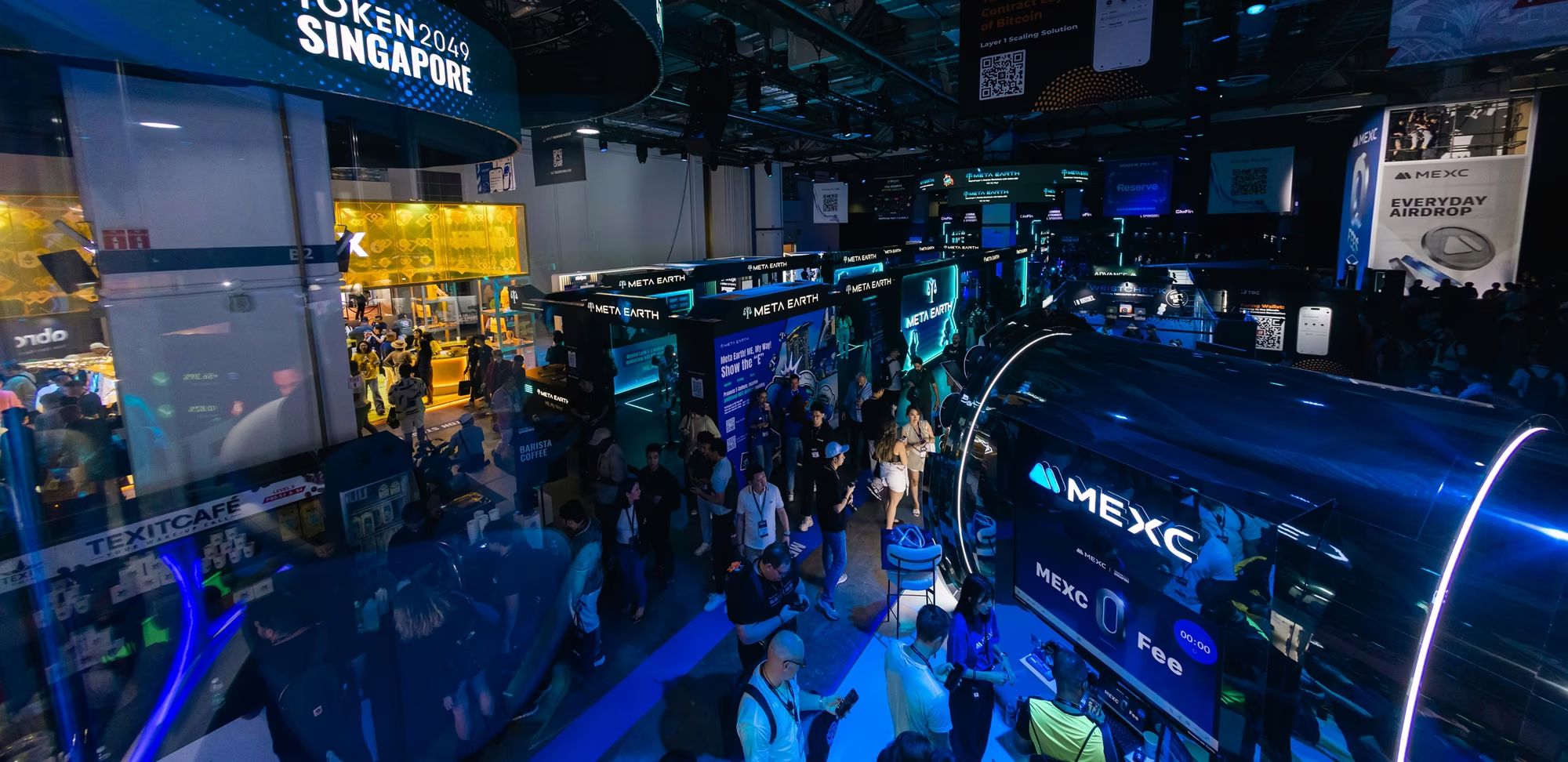 Crowded futuristic exhibition hall with neon-lit Meta Earth and MEXC booths and attendees.