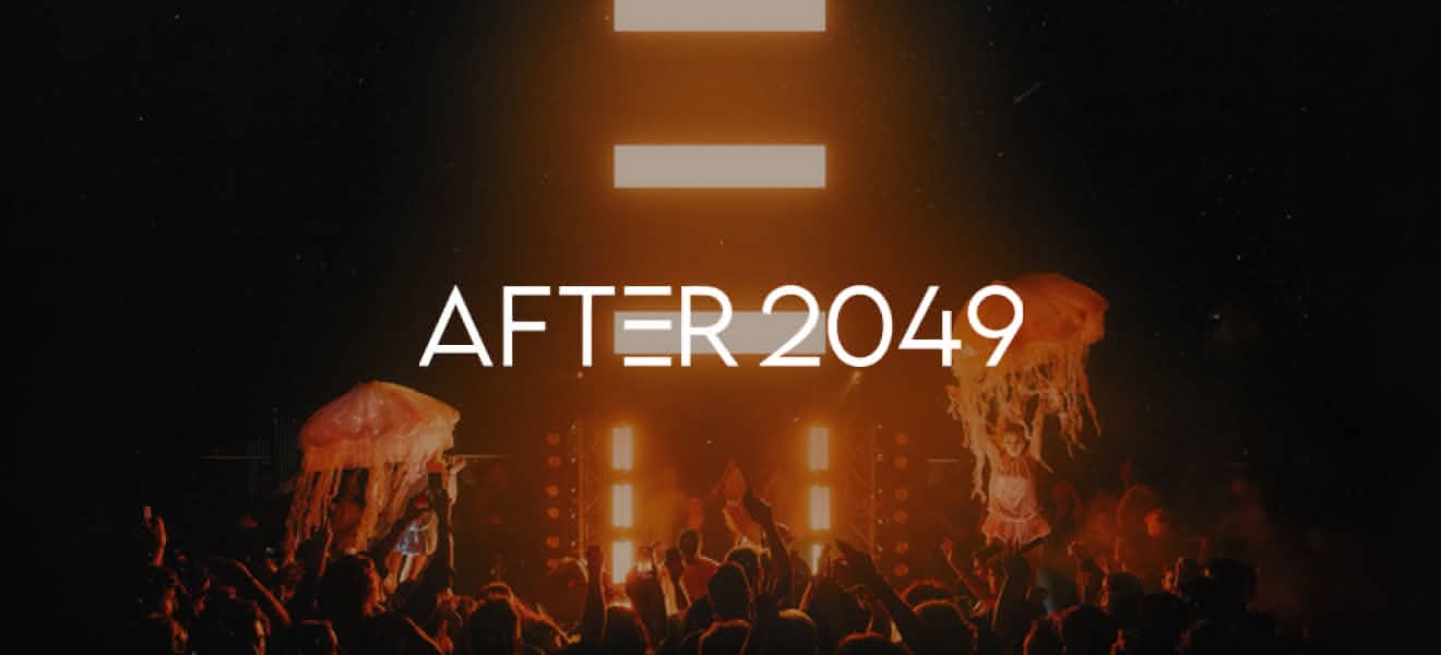 Crowd at a concert or event with two performers holding large illuminated jellyfish props under bright stage lights with the text 'AFTER 2049' centered above them.