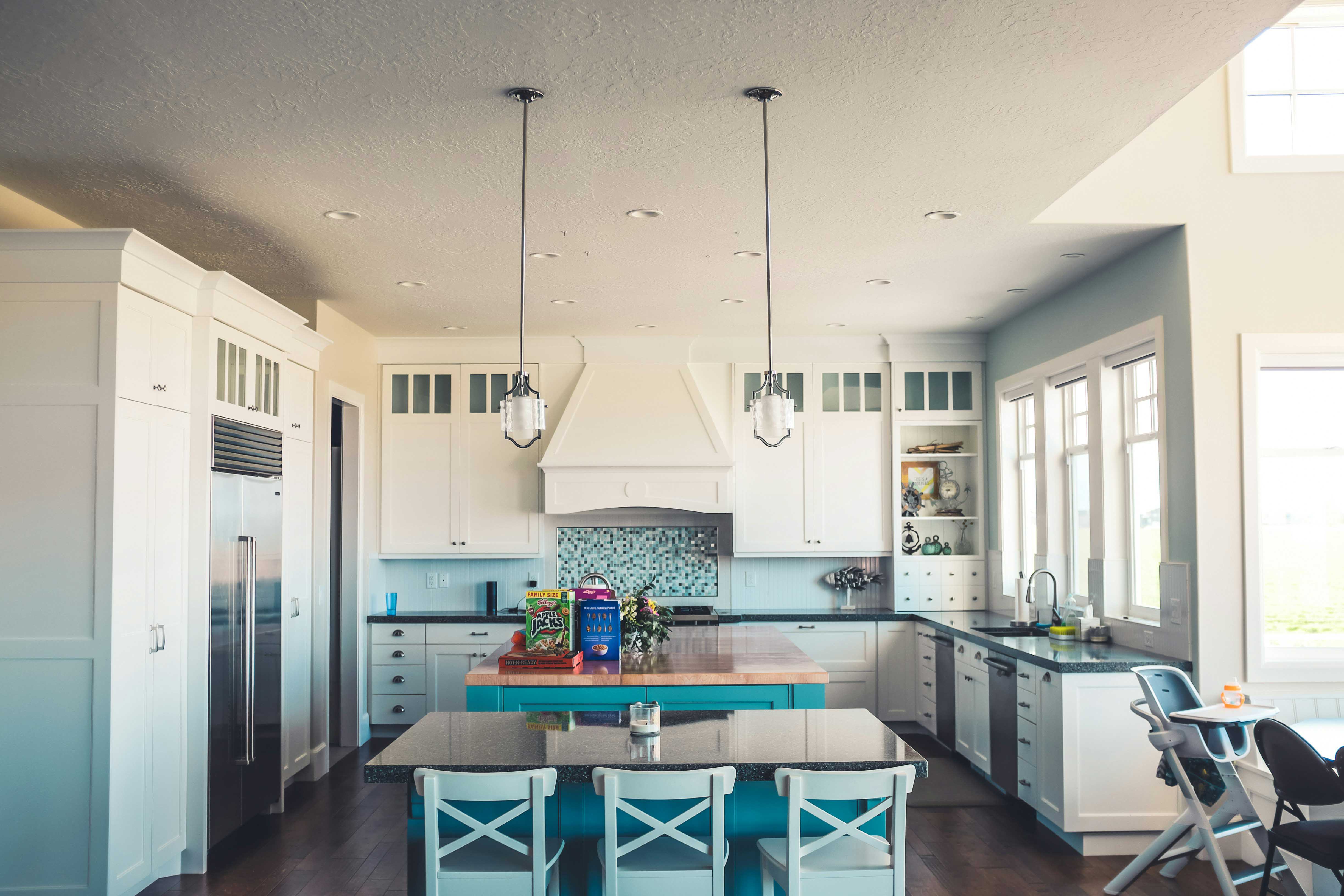 Bright white kitchen with an island and stainless appliances after a deep clean