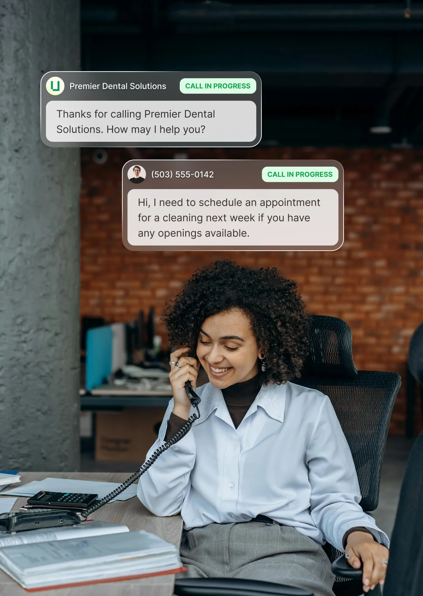 A receptionist is smiling on the phone in an office space while an outsourced receptionist service answers a call for a dental office.