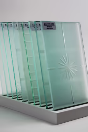 Mehrere vertikal stehende Milchglasplatten mit verschiedenen Texturen und Mustern auf einer weißen Ablage.