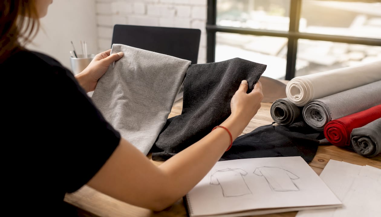Hands comparing two t-shirt fabric samples