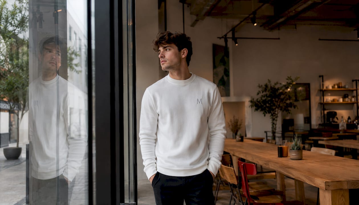 Ein Mann trägt einen schlichten Pullover und arbeitet in seinem Atelier.
